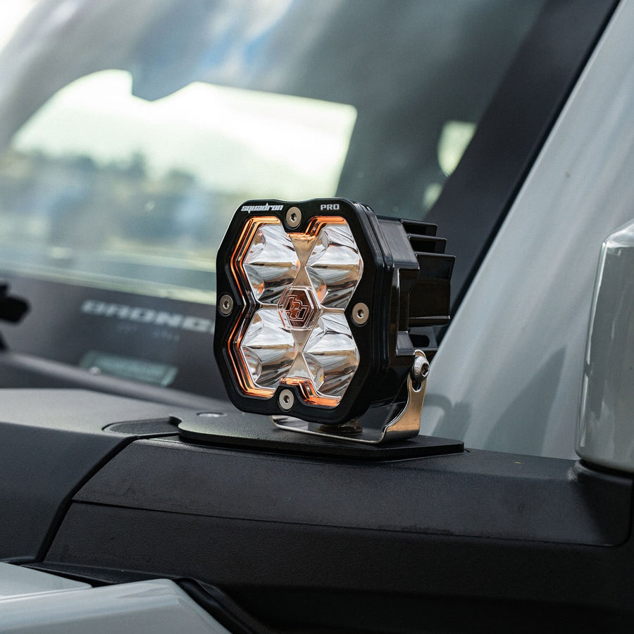 A-Pillar Light Kits by Baja Designs: A Squadron Pro pod with an amber backlight on a cowl mount at the windshield of a Ford Bronco.