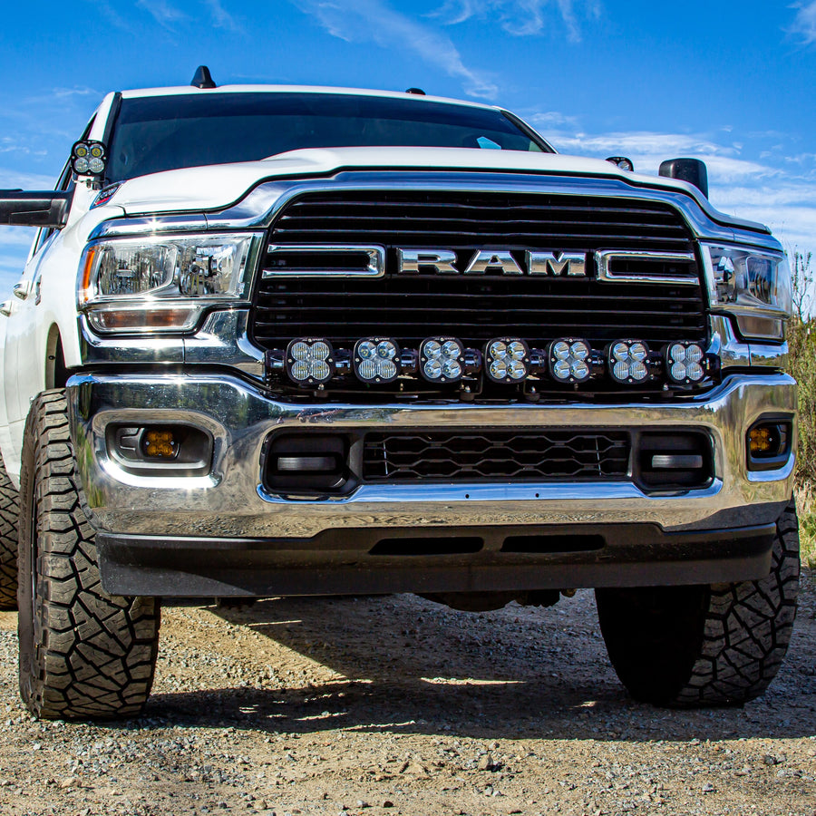 Bumper Light Kits by Baja Designs: Low front view of a white RAM heavy duty pickup with seven XL Sport linkable pods mounted across the lower grille.