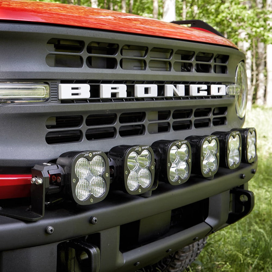 Bumper Light Kits by Baja Designs: A red Ford Bronco front with an XL Linkable light bar across the bumper below the BRONCO grille.