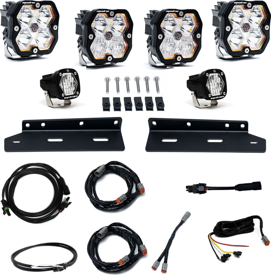 Fog Light Kits by Baja Designs: Fog pocket kit with four square clear lens pods, two small S1 pods, two black brackets, bolts and wiring harnesses on white.