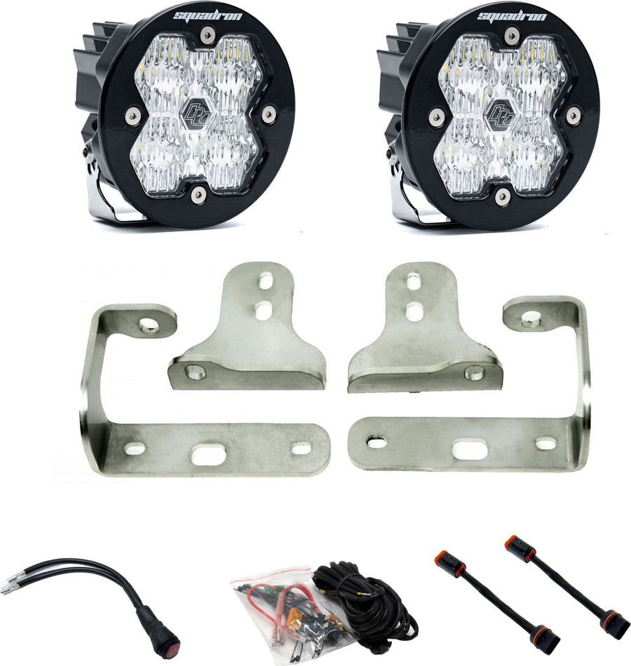 Fog Light Kits by Baja Designs: Pair of round Squadron-R pods with clear lenses, stainless fog pocket brackets, wiring harness and adapters on white.