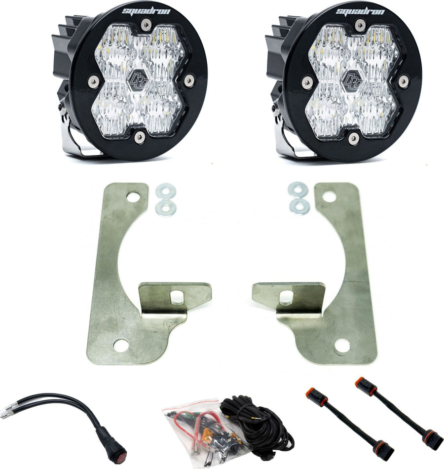 Fog Light Kits by Baja Designs: Pair of round Squadron-R pods with clear lenses, stainless plate fog brackets with spacers, wiring harness and adapters on white.