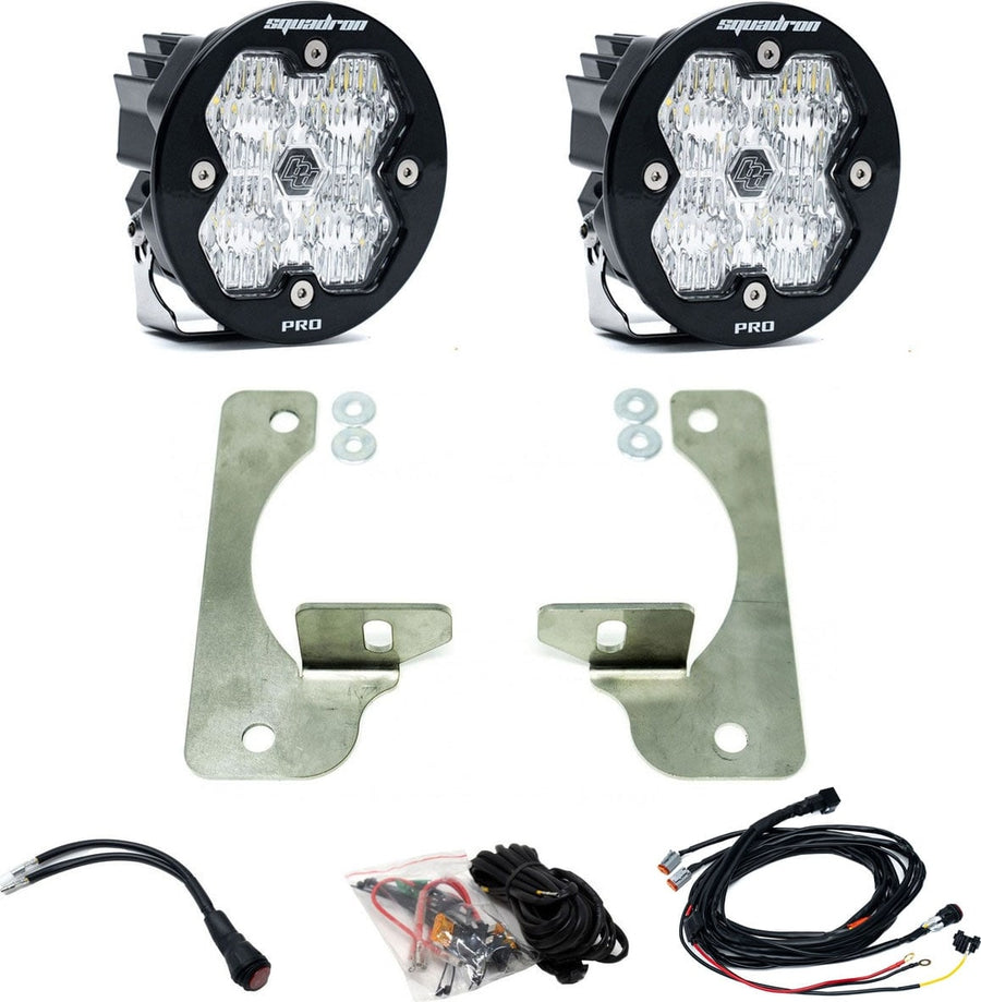Fog Light Kits by Baja Designs: Pair of round Squadron-R Pro pods with clear lenses, stainless plate fog brackets with spacers, wiring harness and adapters on white.