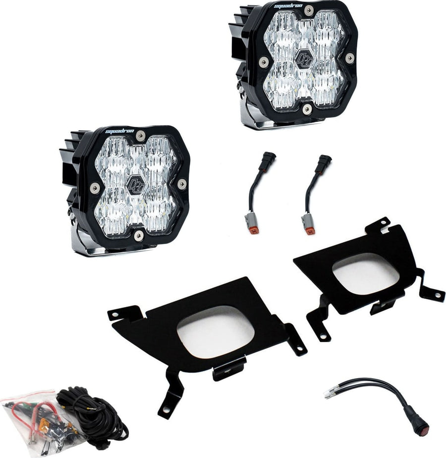 Fog Light Kits by Baja Designs: Pair of square Squadron pods with clear lenses, two black fog pocket brackets, wiring harness and adapters on white.