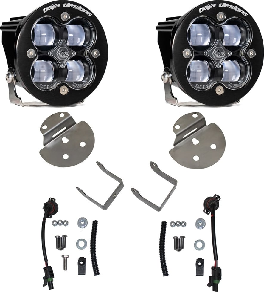Fog Light Kits by Baja Designs: Pair of round Squadron-R fog pods with clear lenses, round mounting plates, angled brackets, pigtail harnesses and hardware on white.