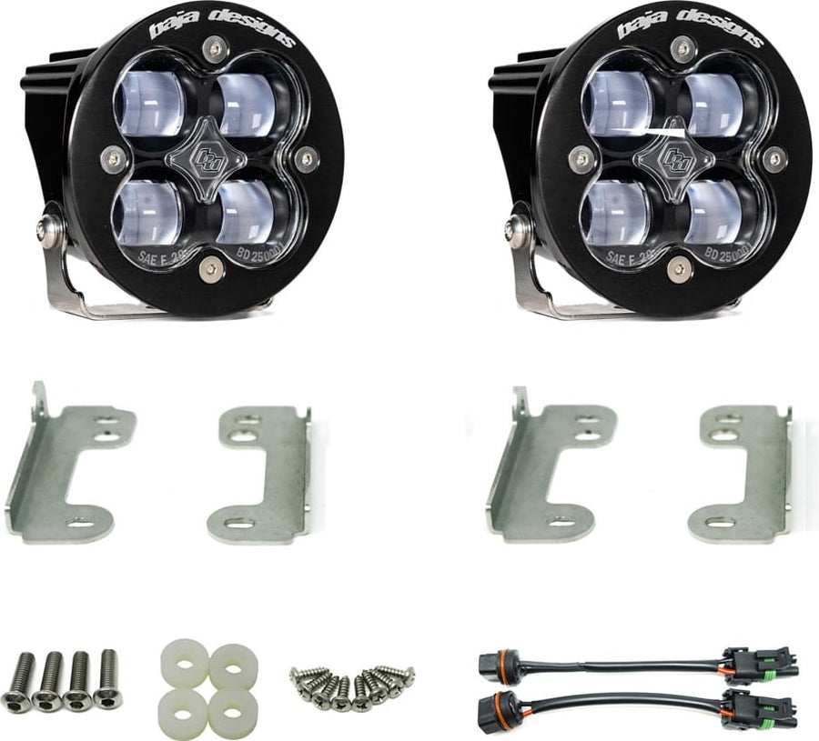 Fog Light Kits by Baja Designs: Pair of round Squadron-R fog pods with clear lenses, four steel brackets, hardware and two adapter harnesses on white.
