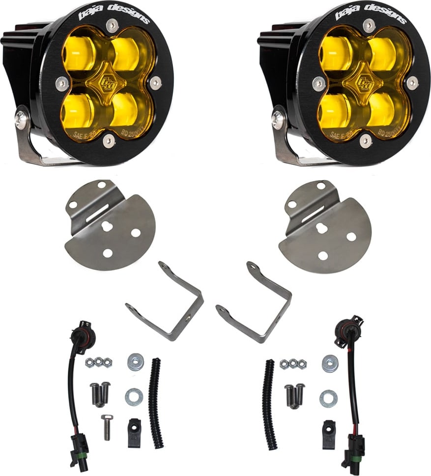 Fog Light Kits by Baja Designs: Pair of round Squadron-R fog pods with amber lenses, round mounting plates, angled brackets, pigtail harnesses and hardware on white.