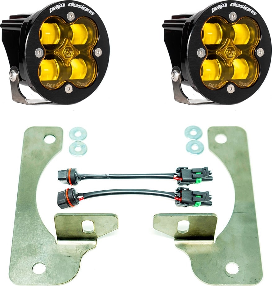 Fog Light Kits by Baja Designs: Pair of round Squadron-R fog pods with amber lenses, two large flat steel brackets, washers and two adapter harnesses on white.