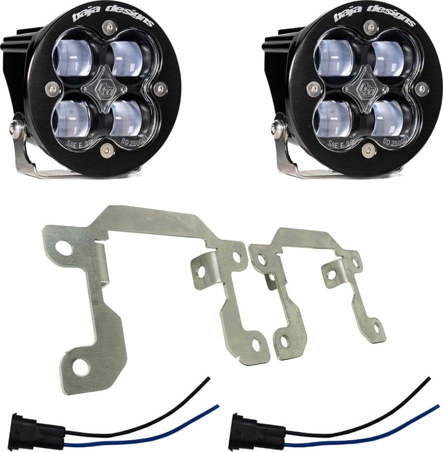 Fog Light Kits by Baja Designs: Two round black Squadron SAE fog pods with clear lenses, two silver mounting brackets and two pigtail harnesses on white.