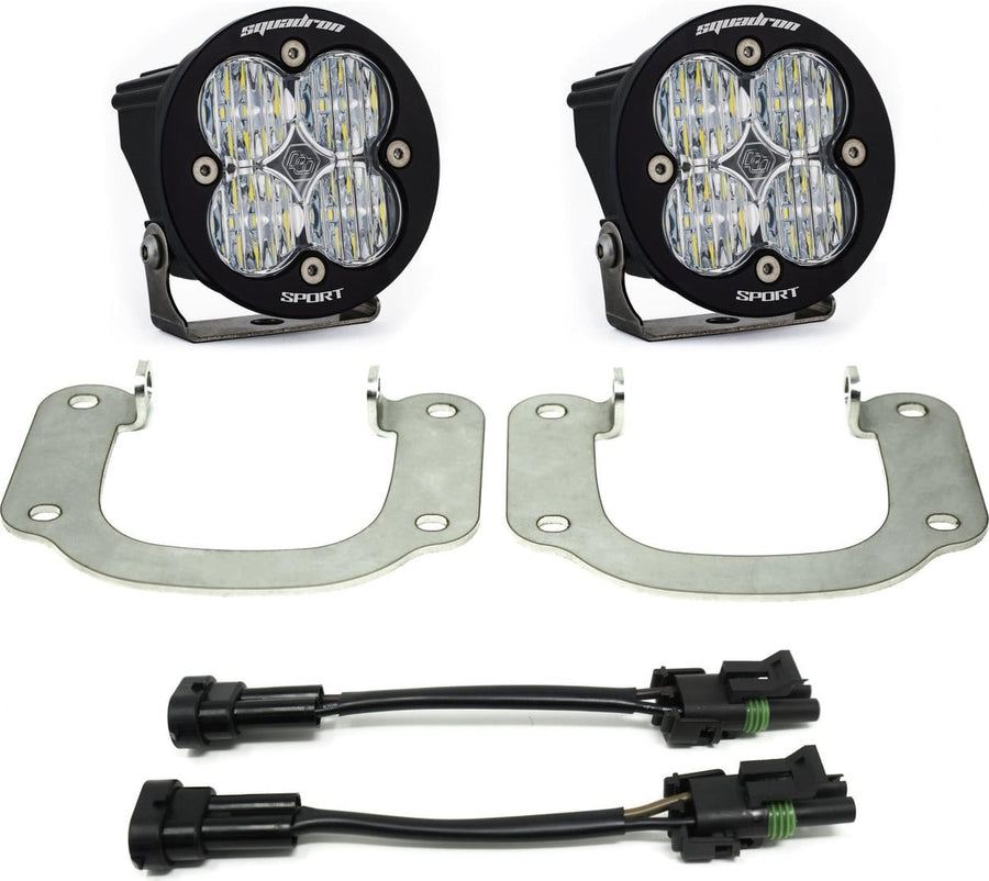 Fog Light Kits by Baja Designs: Two round black Squadron Sport pods with clear lenses, two silver hoop brackets and two adapter harnesses on white.