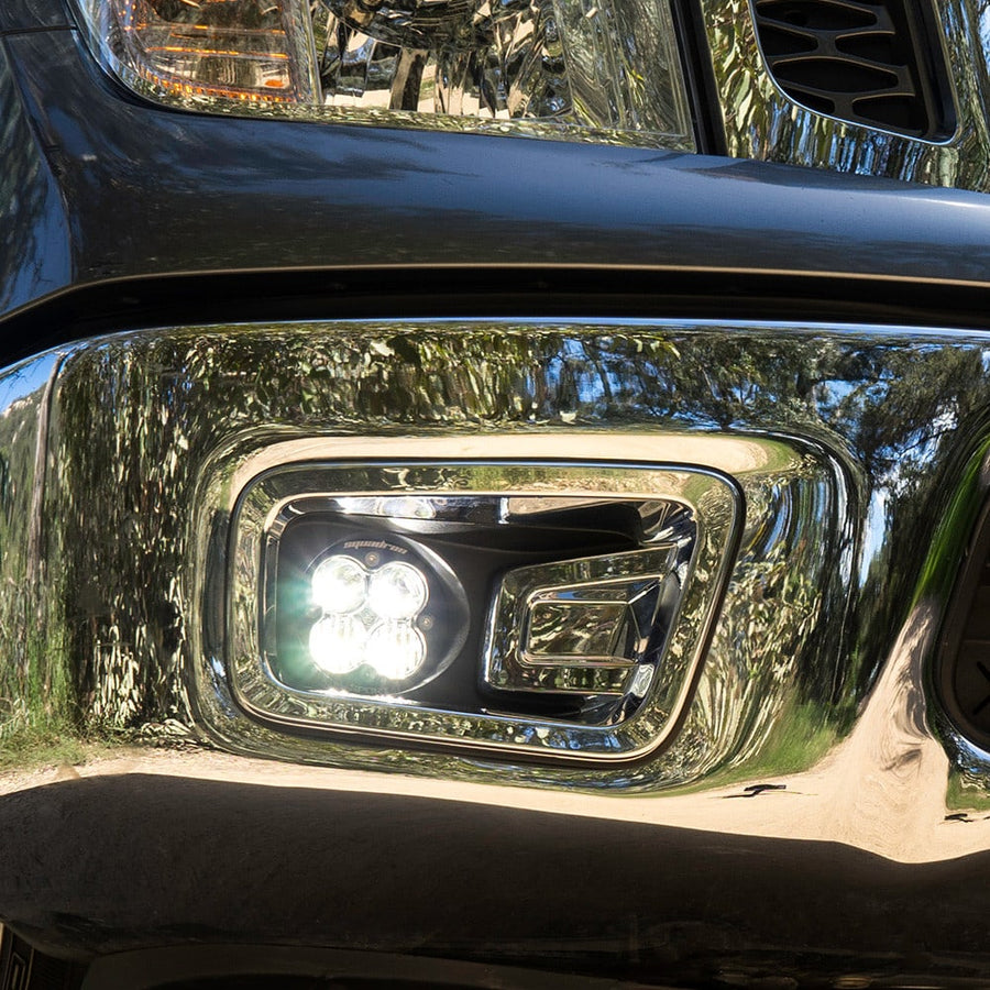 Fog Light Kits by Baja Designs: Close view of a clear Squadron fog light glowing inside a chrome fog pocket bezel.