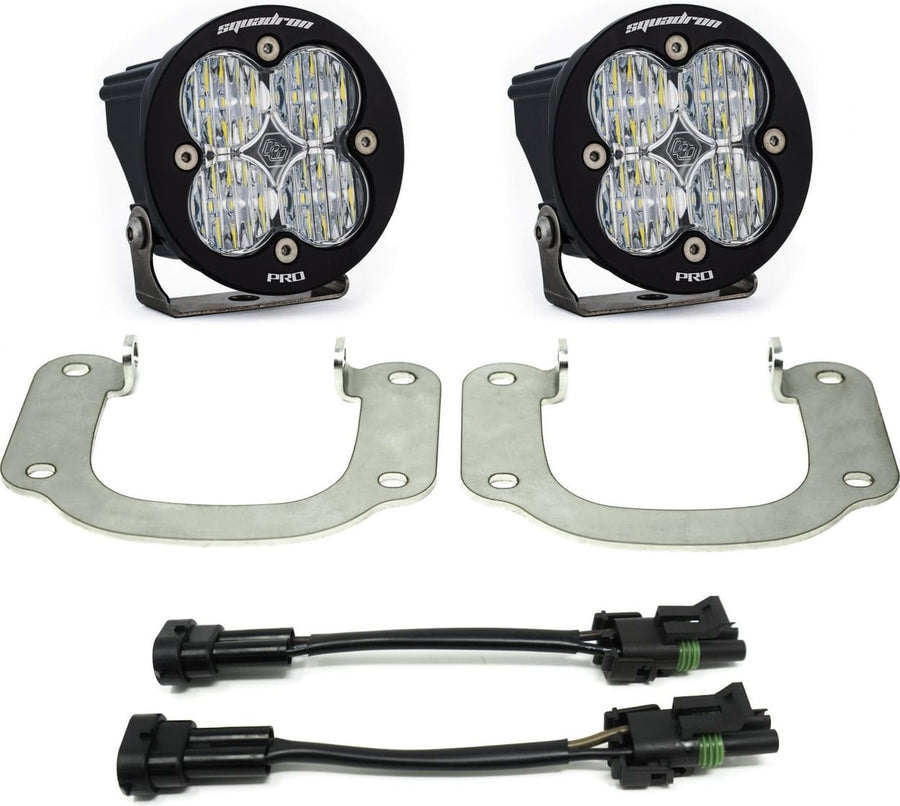 Fog Light Kits by Baja Designs: Two round black Squadron Pro pods with clear lenses, two silver hoop brackets and two adapter harnesses on white.