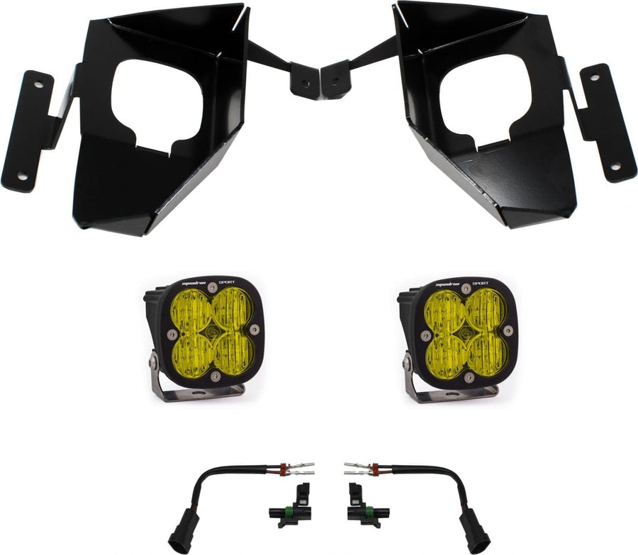 Fog Light Kits by Baja Designs: Pair of black Squadron Sport fog pods with amber lenses, two black fog pocket brackets and two adapter harnesses on white.