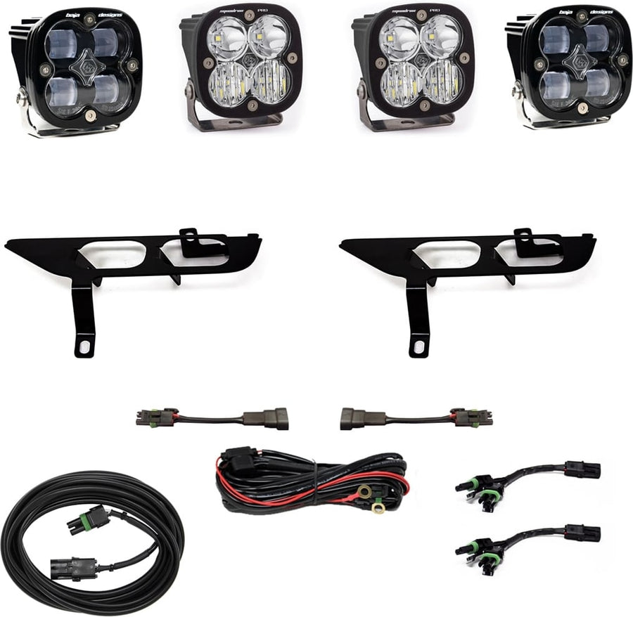 Fog Light Kits by Baja Designs: Four black Squadron pods with clear lenses, two black fog pocket brackets, a red relay harness, adapter harnesses and coiled cables on white.