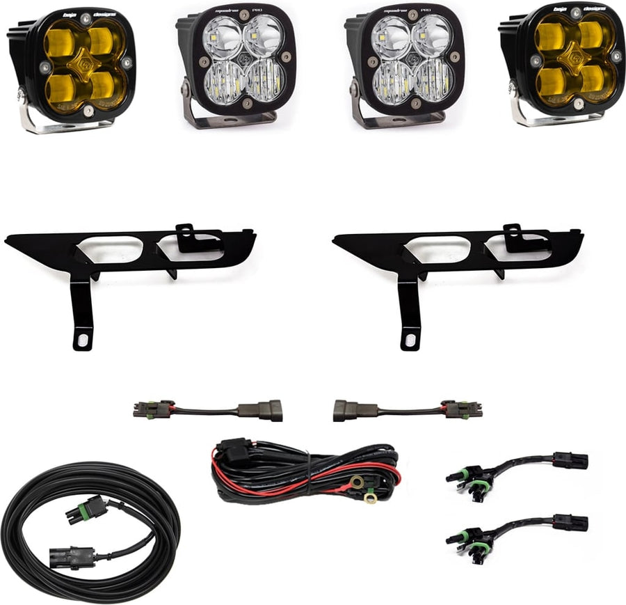 Fog Light Kits by Baja Designs: Four black Squadron pods, two amber and two clear, two black fog pocket brackets, a red relay harness, adapter harnesses and coiled cables on white.