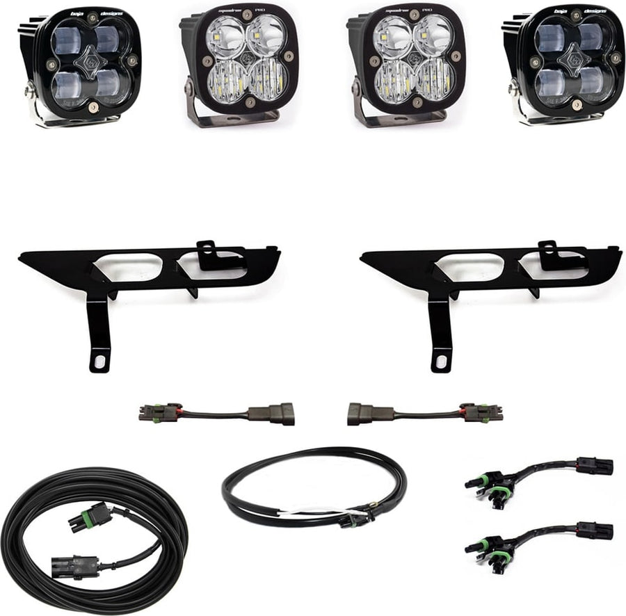 Fog Light Kits by Baja Designs: Four black Squadron pods with clear lenses, two black fog pocket brackets, adapter harnesses and coiled cables on white.