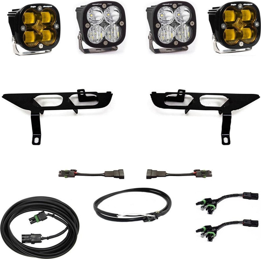 Fog Light Kits by Baja Designs: Four black Squadron pods, two amber and two clear, two black fog pocket brackets, adapter harnesses and coiled cables on white.