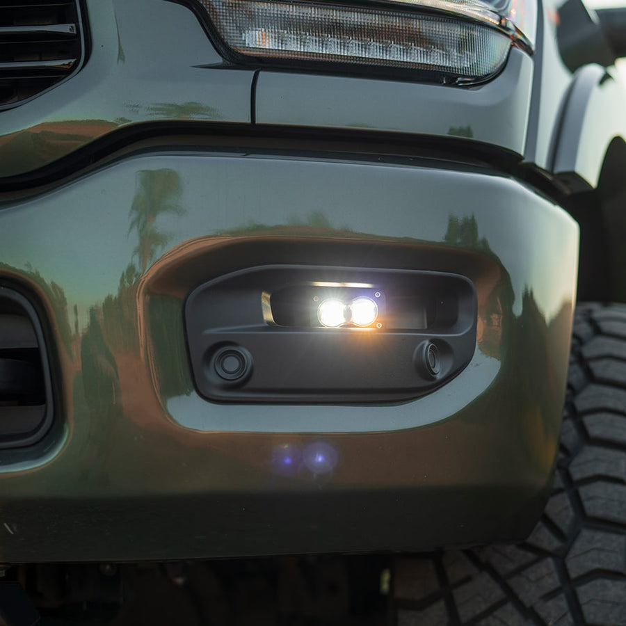 Fog Light Kits by Baja Designs: Close view of a gray Ram heavy duty bumper with a lit S2 pod in the fog pocket under the headlight.