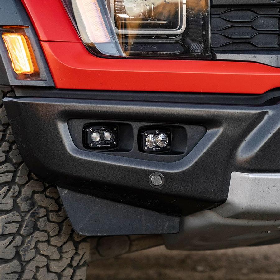 Fog Light Kits by Baja Designs: Close view of a red Ford Raptor front bumper with two unlit S2 pods in the fog pocket.