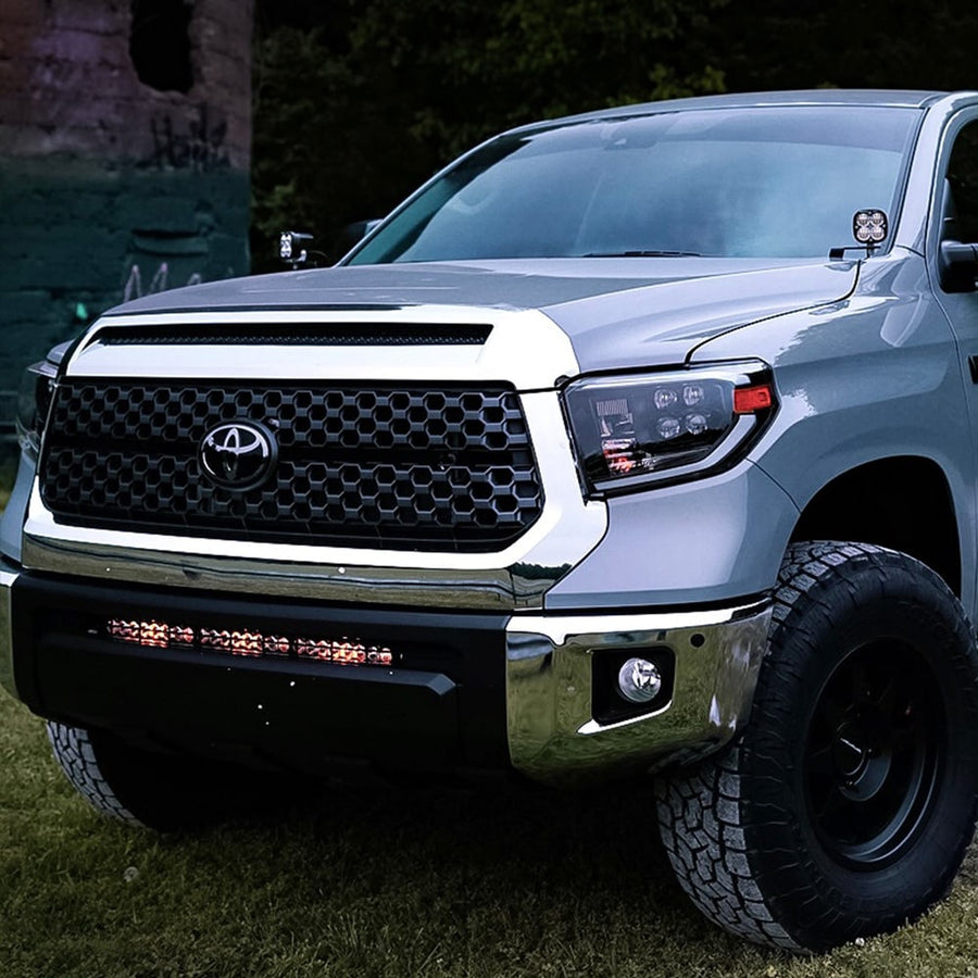 Grille Light Kits by Baja Designs: A silver Toyota Tundra on grass with a lit S8 light bar glowing in the lower grille opening.