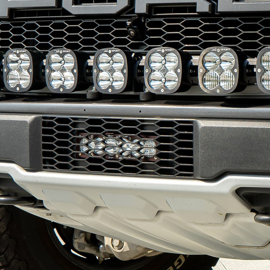 Grille Light Kits by Baja Designs: Close view of a truck front bumper with a lit short light bar in the lower grille below a row of square pods.