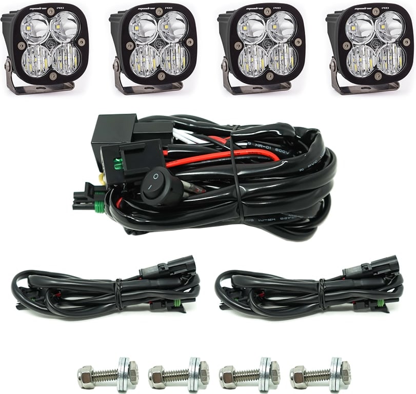 Grille Light Kits by Baja Designs: Four Squadron Pro pods with clear lenses, a switch harness, two extension harnesses and four mounting bolts on white.