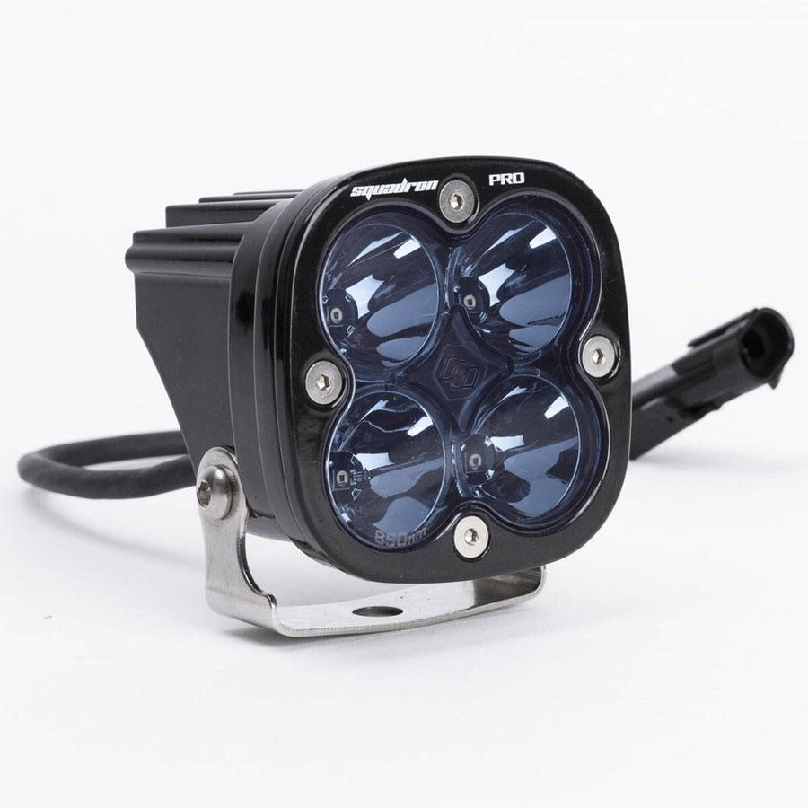 Laser & Infrared Lights by Baja Designs: A black Squadron Pro LED pod with four smoked optics on a stainless bracket with its wiring pigtail on white.