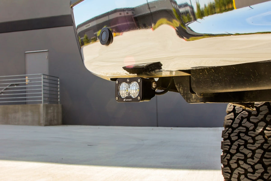 Reverse Light Kits by Baja Designs: An S2 pod mounted beneath a chrome rear bumper next to an off-road tire.