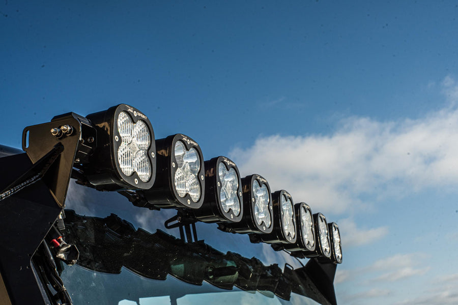 Roof Light Kits by Baja Designs: A row of square LED pods on a linkable roof bar is seen from below against a blue sky.