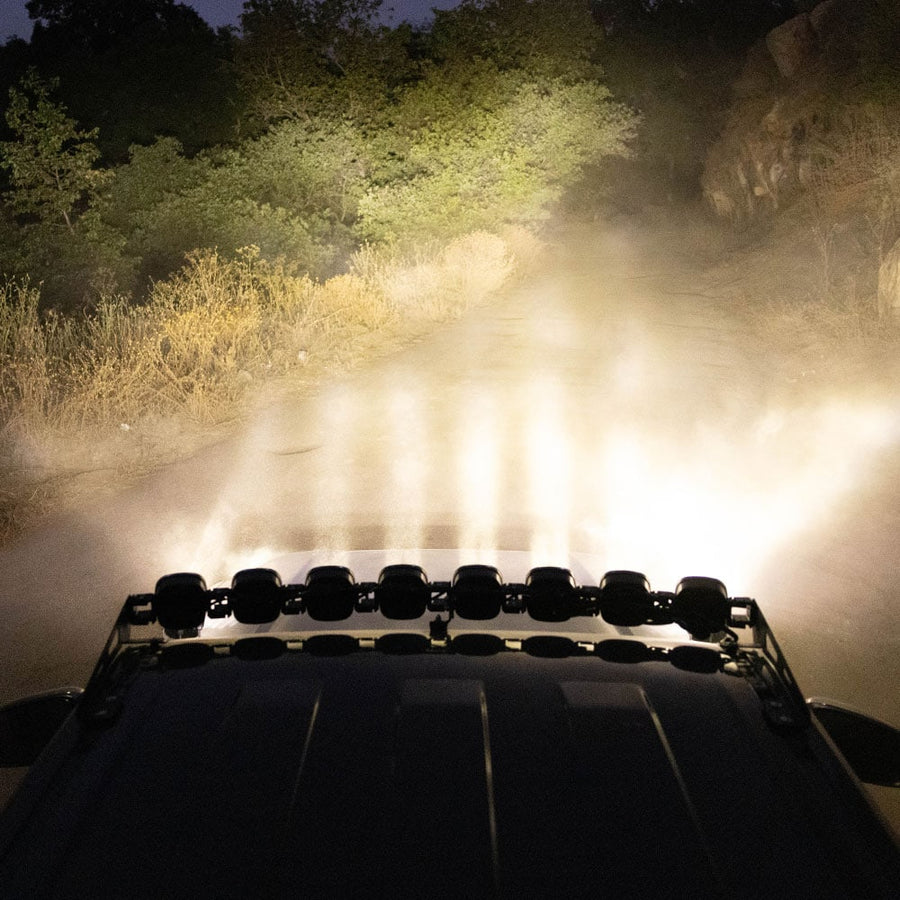 Roof Light Kits by Baja Designs: A lit linkable LED roof bar throws bright white light down a dusty wooded trail at night.