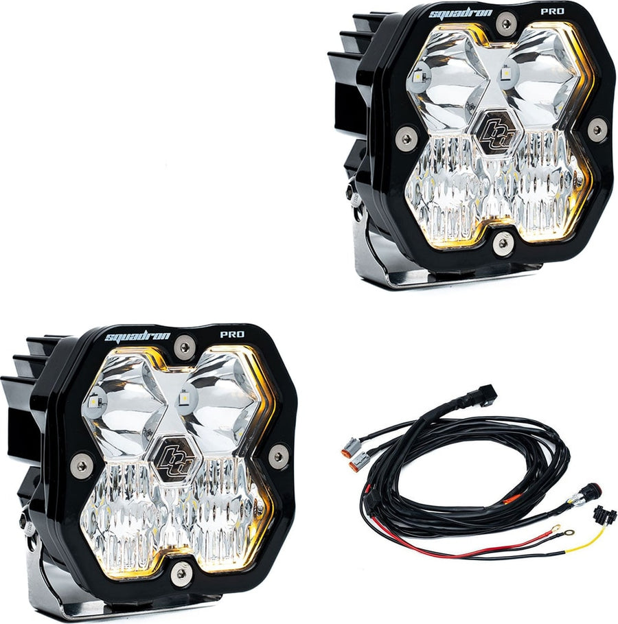 Squadron Light Pods by Baja Designs: Pair of black Squadron Pro pods with clear driving combo lenses and amber backlight glow, with wiring harness, on white.