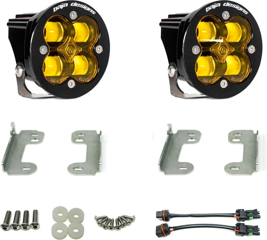 Fog Light Kits by Baja Designs: A pair of black Squadron-R pods with amber lenses laid out with fog pocket brackets, hardware and adapter pigtails on white.
