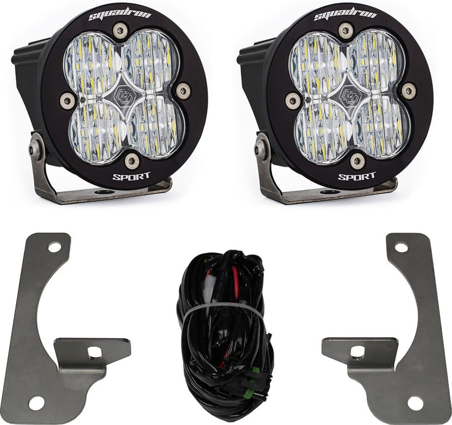 Fog Light Kits by Baja Designs: A pair of black Squadron Sport pods with clear lenses shown with two fog pocket brackets and a wiring harness on white.