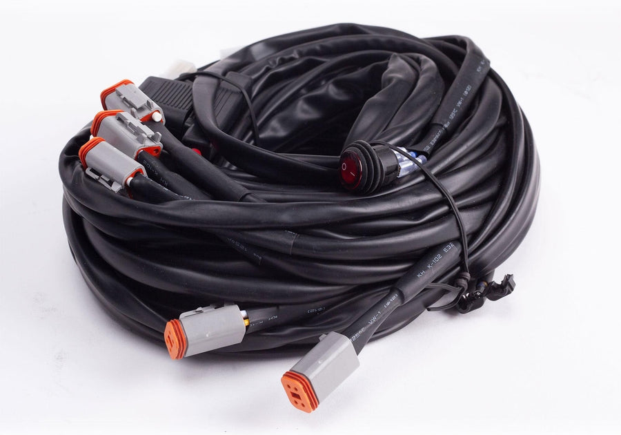Wiring Harnesses by Baja Designs: A coiled multi light wiring harness with gray Deutsch connectors and a switch on white.