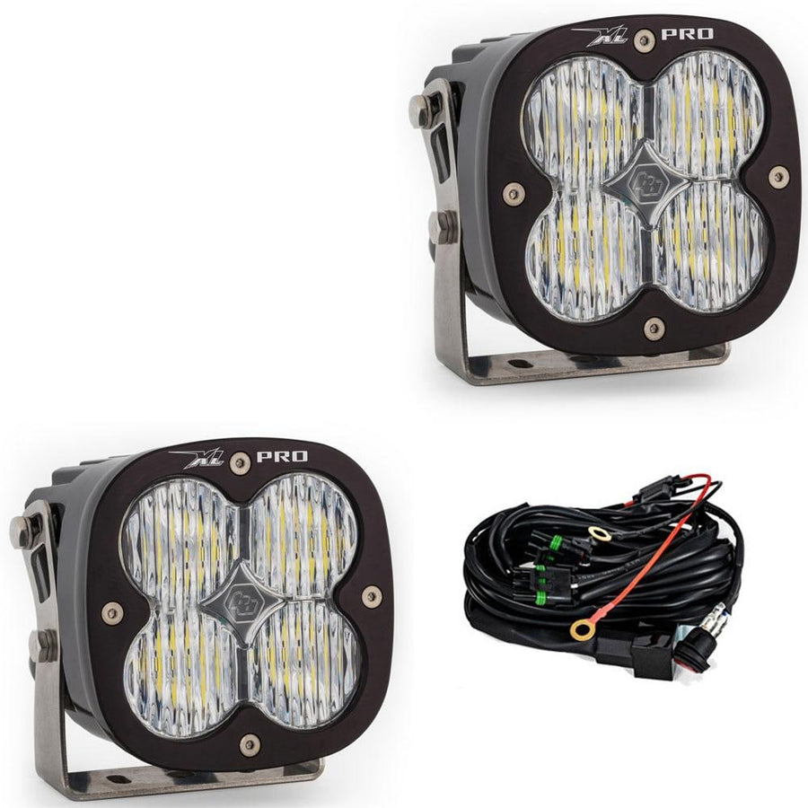 XL Light Pods by Baja Designs: A pair of black XL Pro LED light pods with clear wide cornering lenses on stainless brackets, shown with the wiring harness on a white background.