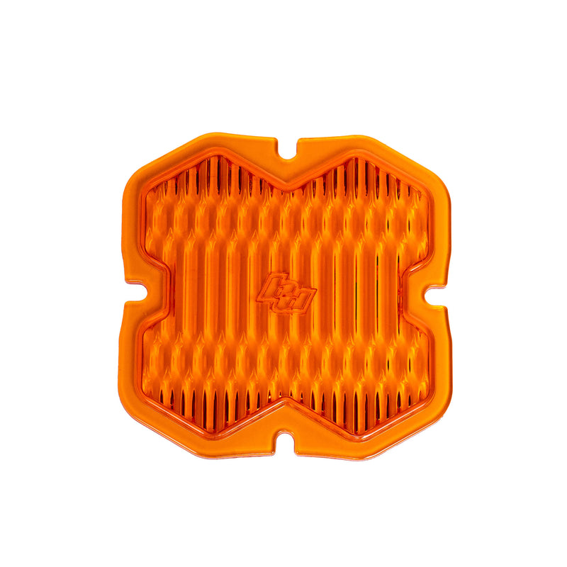 Baja Designs Squadron 2.0 Light Pod 90° Lens Kit, complete kit on a studio background: A orange factory amber Squadron pod lens with a wide cornering optic pattern and a molded Baja Designs logo, shown flat on a white background