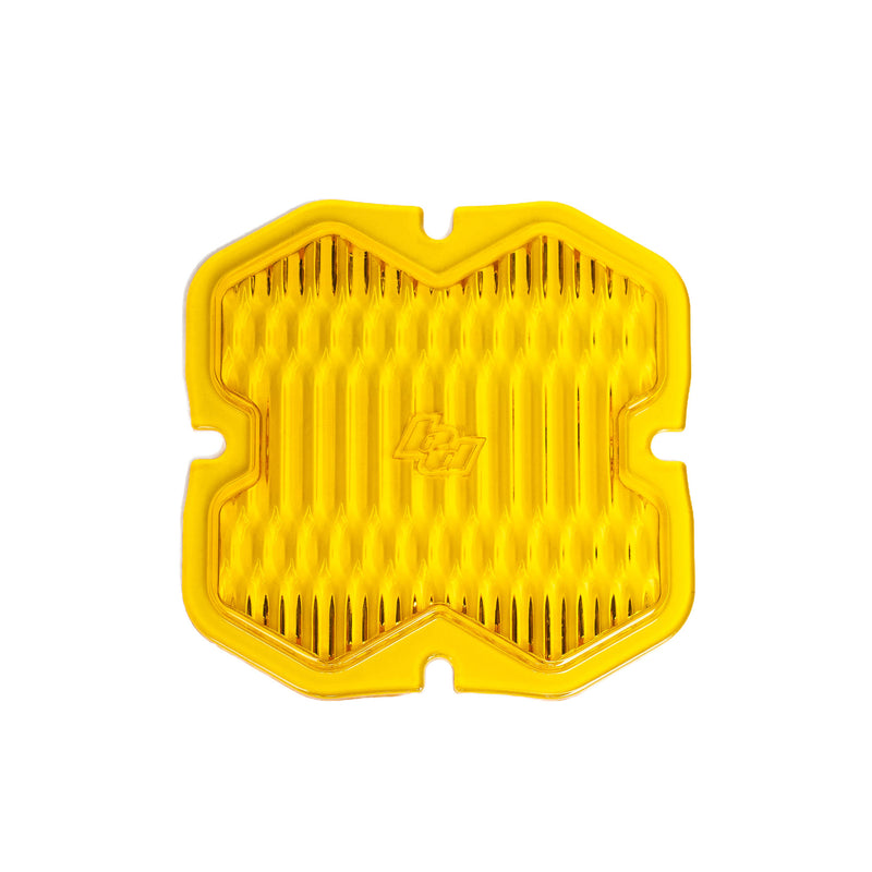 Baja Designs Squadron 2.0 Light Pod 90° Lens Kit, complete kit on a studio background: A yellow Baja Amber Squadron pod lens with a wide cornering optic pattern and a molded Baja Designs logo, shown flat on a white background