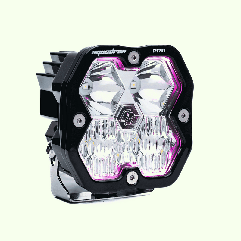Baja Designs Squadron 2.0 Pro Black LED Auxiliary Light Pod Pair, whole product on a studio background: single black Squadron Pro pod with clear driving combo lens and magenta backlight glowing, on a pale green background. Pair product shows only one