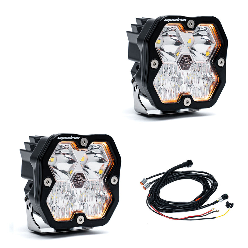 Baja Designs Squadron 2.0 Sport Black LED Auxiliary Light Pod Pair, whole product on a studio background: A pair of black Squadron LED pods with clear driving combo lenses and a wiring harness on a white background