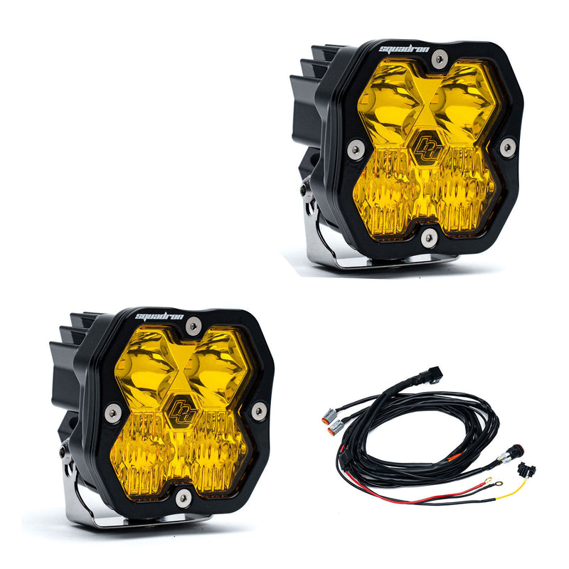 Baja Designs Squadron 2.0 Sport Black LED Auxiliary Light Pod Pair, whole product on a studio background: A pair of black Squadron LED pods with amber driving combo lenses and a wiring harness on a white background