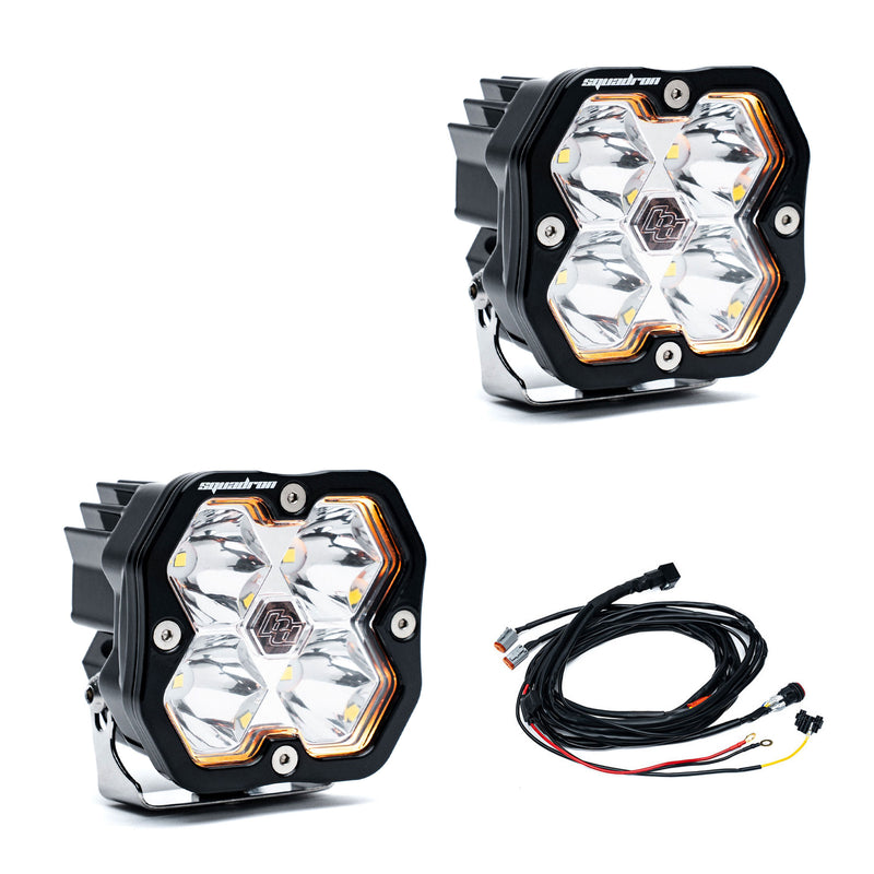 Baja Designs Squadron 2.0 Sport Black LED Auxiliary Light Pod Pair, whole product on a studio background: A pair of black Squadron LED pods with clear spot lenses and a wiring harness on a white background