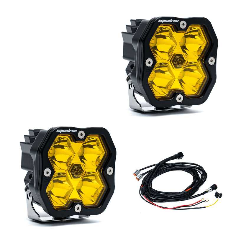 Baja Designs Squadron 2.0 Sport Black LED Auxiliary Light Pod Pair, whole product on a studio background: A pair of black Squadron LED pods with amber spot lenses and a wiring harness on a white background