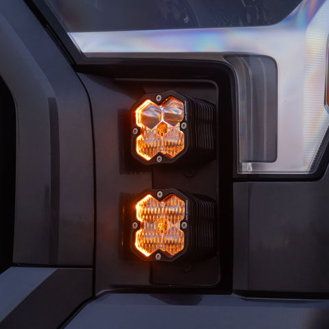 Baja Designs Squadron 2.0 Sport Vent Kit on a Toyota Tundra: two stacked Squadron pods glow amber in the vent pocket beside the headlight of a dark gray truck