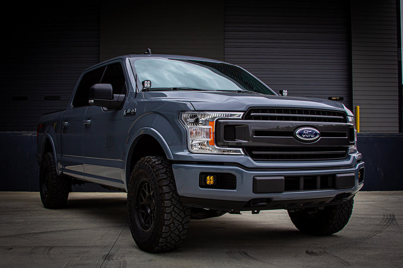 Baja Designs Squadron Pro A-Pillar Light Kit installed on a Ford F-150: A gray Ford F-150 seen from the front three-quarter with a Squadron pod on the A-pillar