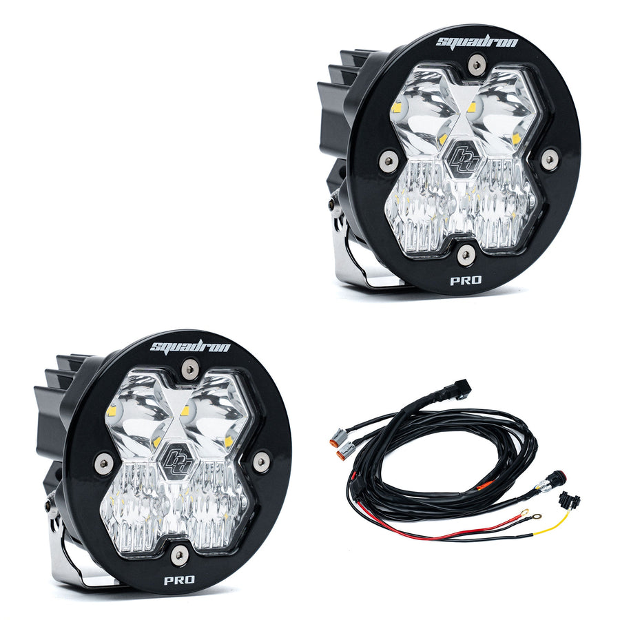 Squadron Light Pods by Baja Designs: A pair of round black Squadron-R LED pods with clear diffused lenses and a wiring harness on a white background