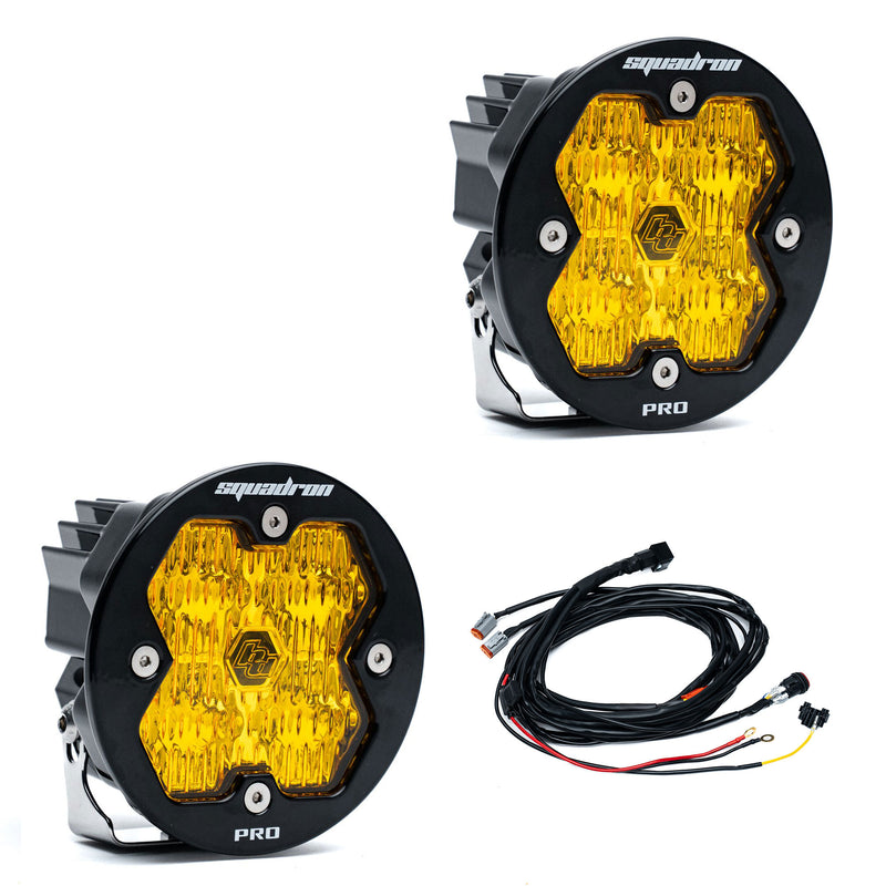 Baja Designs Squadron-R 2.0 Pro Black LED Auxiliary Light Pod Pair, whole product on a studio background: A pair of round black Squadron-R Pro LED pods with amber lenses and a wiring harness on a white background