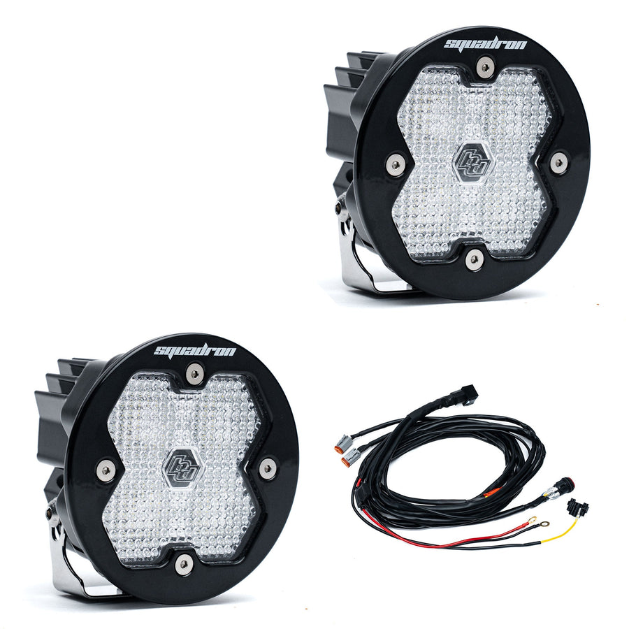 Squadron Light Pods by Baja Designs: A pair of round black Squadron-R LED pods with clear diffused lenses and a wiring harness on a white background