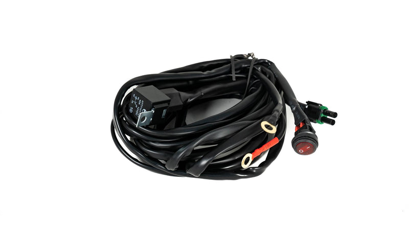Baja Designs Squadron/S2/S1 On/Off 2-Pin Single Light Wiring Harnes, whole product on a studio background: A coiled black wiring harness with a relay, a red rocker switch, ring terminals and a 2-pin weatherproof connector