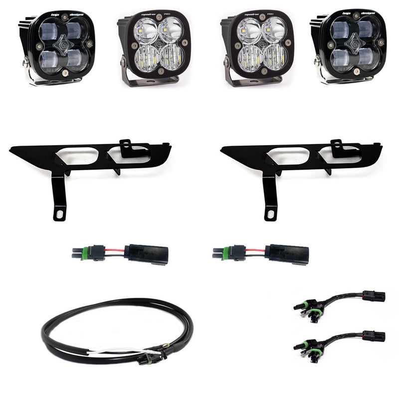 Baja Designs Squadron SAE/Pro Fog Pocket Light Kit, complete kit on a studio background: four square Squadron pods, two black fog pocket brackets, pigtail adapters and harness, all clear lenses laid out on a white background. Lens color differs from