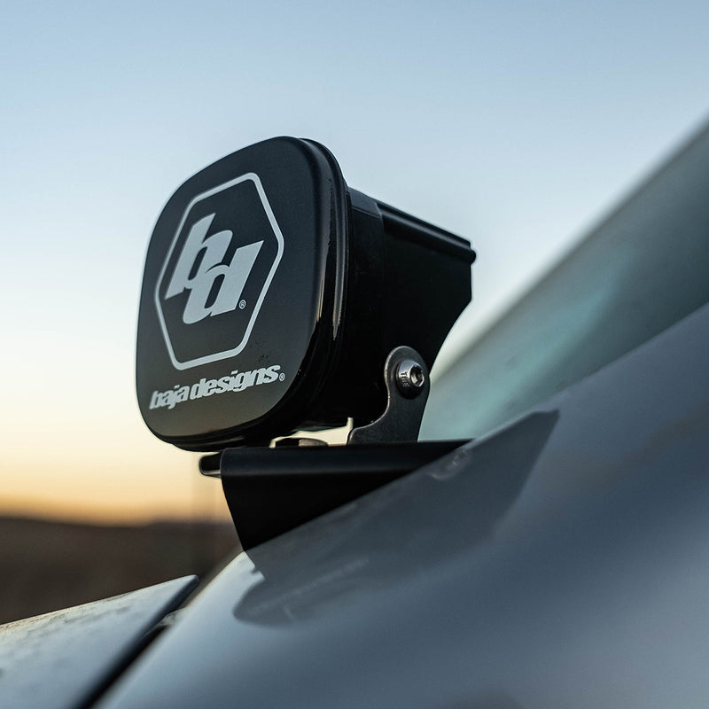 Baja Designs Squadron Single Rock Guard on a vehicle: A Squadron light with a black Baja Designs rock guard on a pillar mount against a dusk sky, vehicle not identifiable